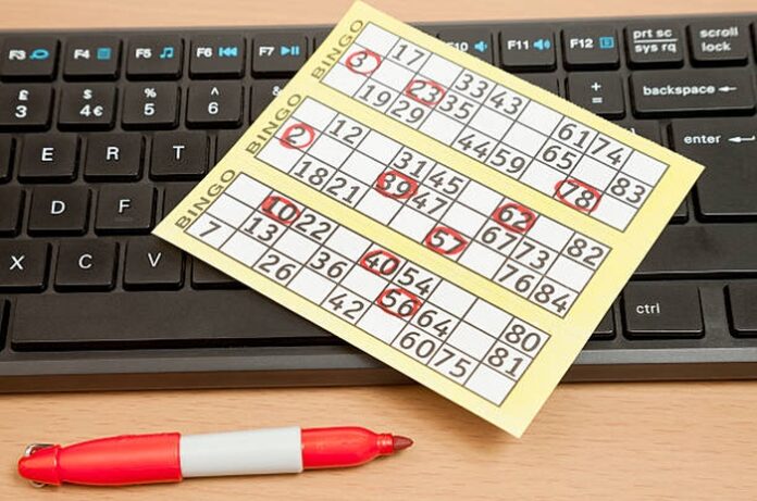A bingo card and marker pen resting by a computer keyboard.