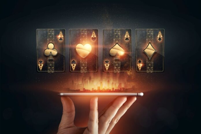 In the hands of a smartphone with playing cards, black-gold background. Concept of online gambling, online casino. Copy space.