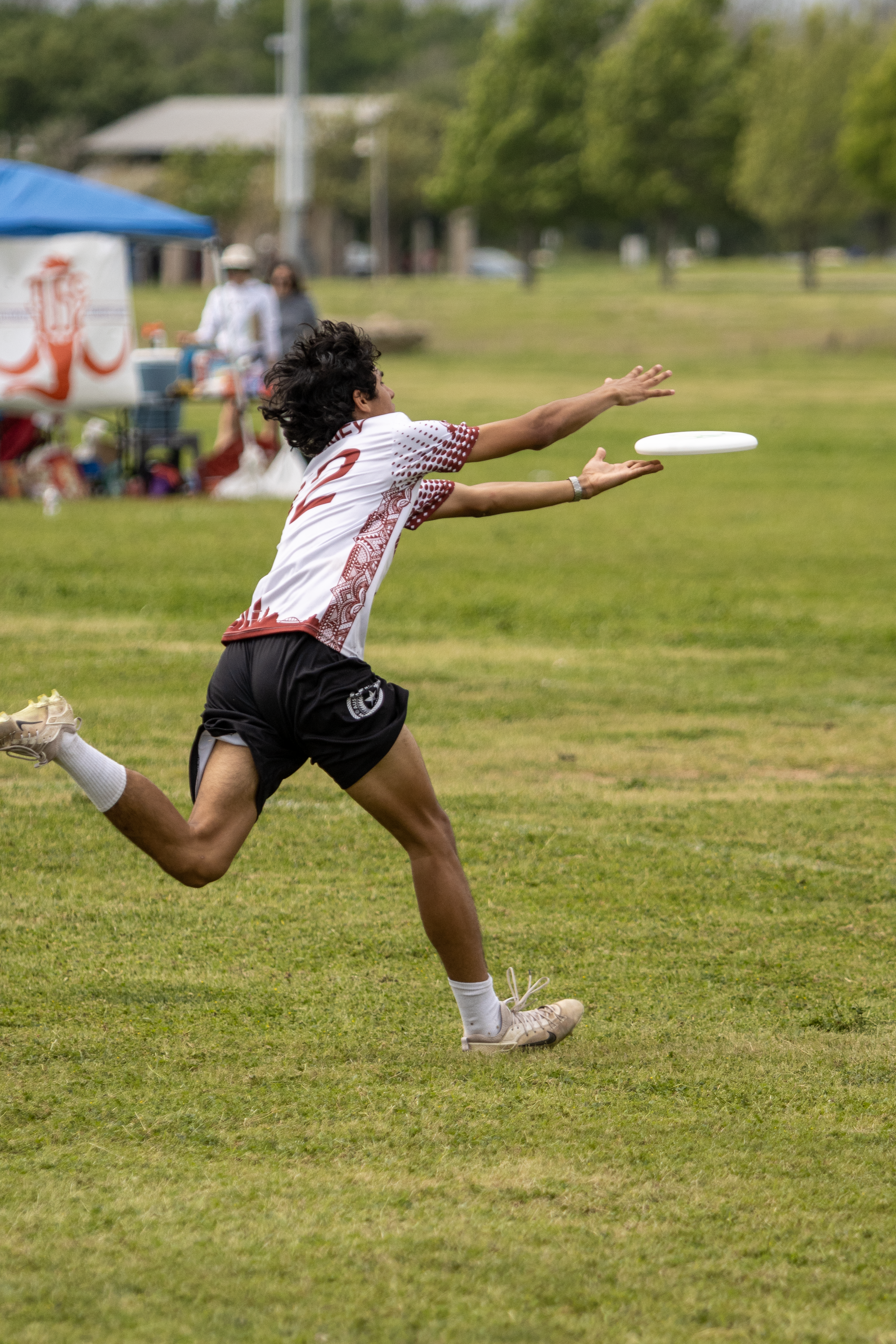 Athlete in sportswear leaps to catch a frisbee during a park game.