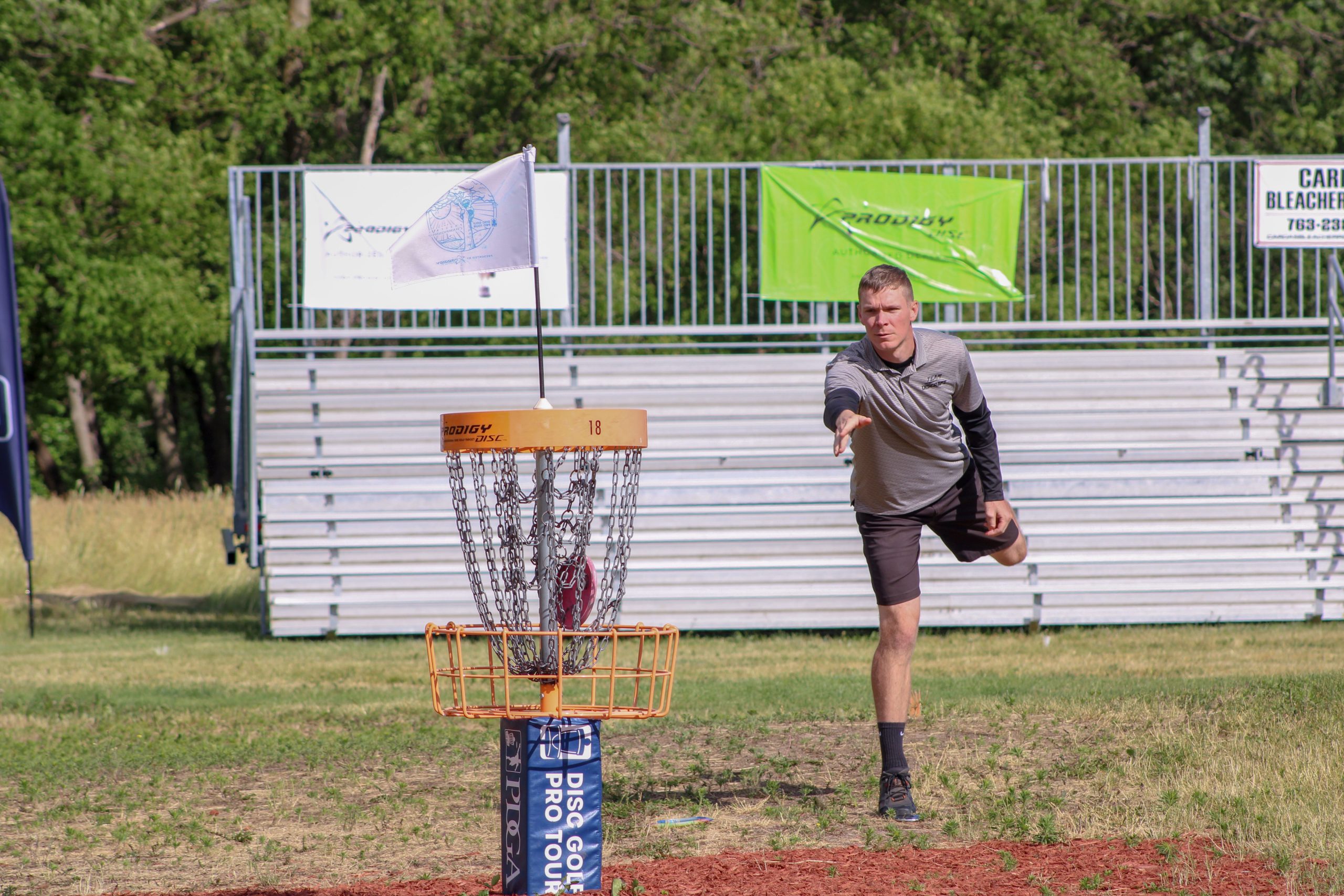 A man throws a disc towards the basket during a disc golf tournament in Clearwater, MN.
