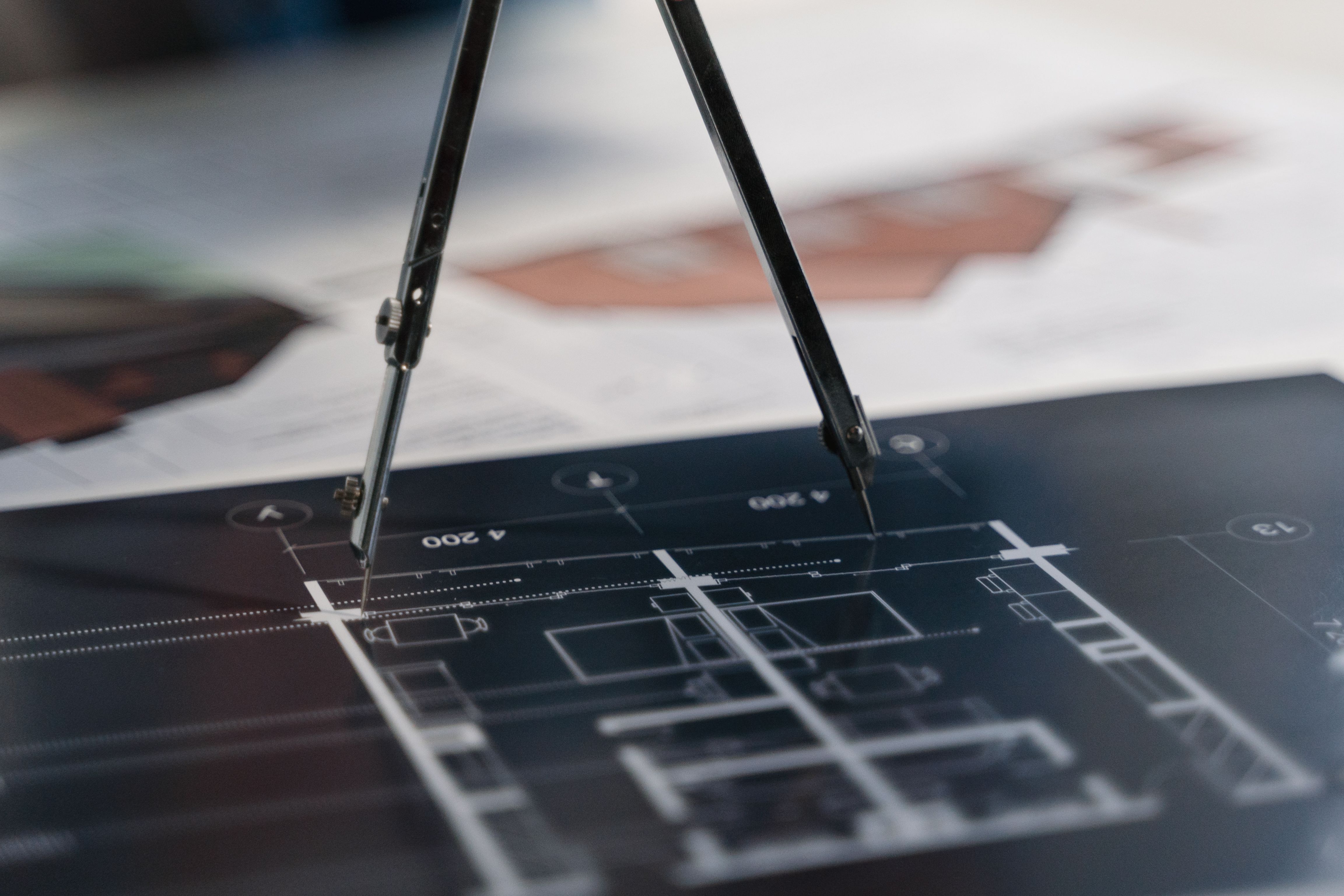 Compass resting on architectural blueprints showing planning and measurement for a build
