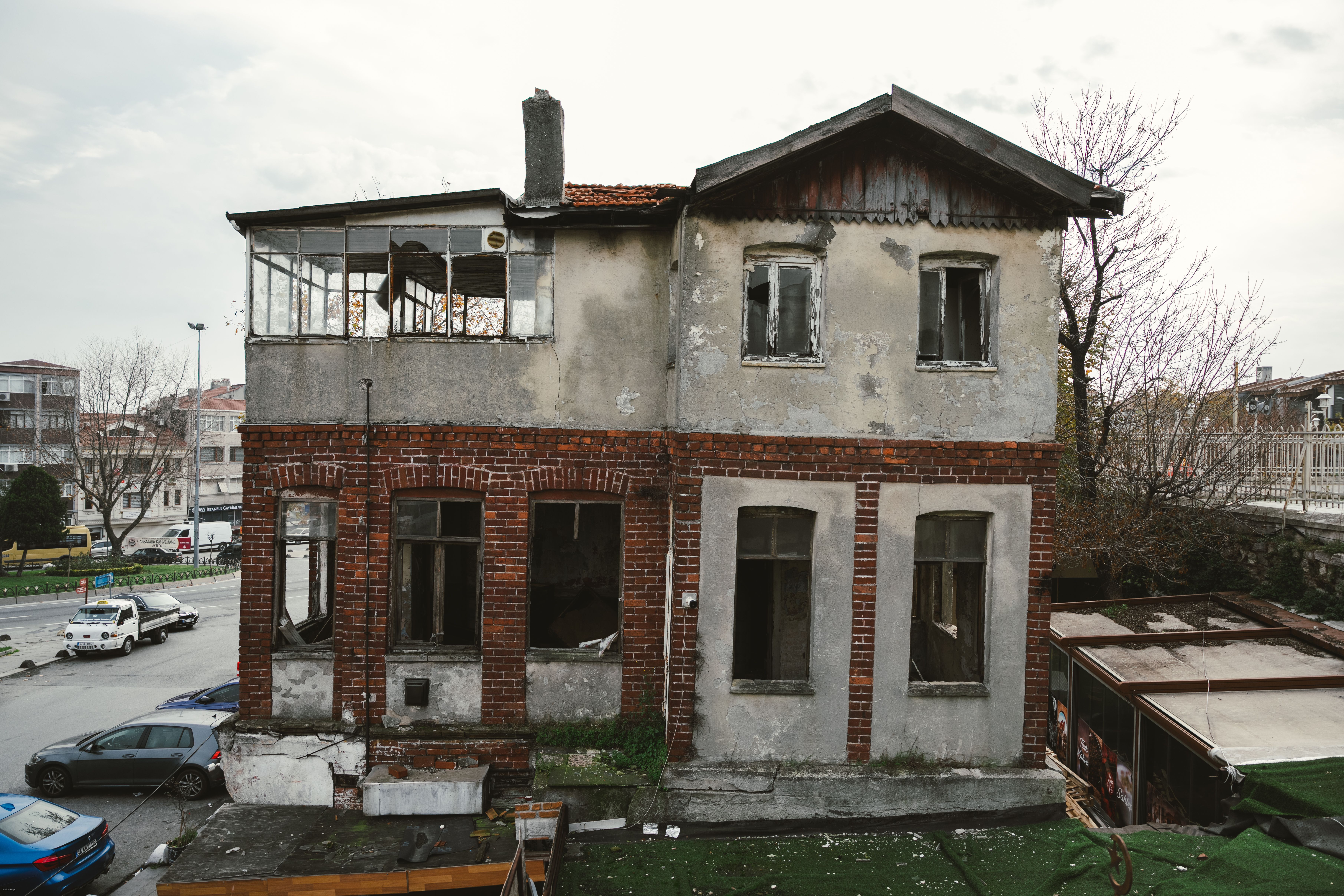 Deteriorated house with brick facade and broken windows showing severe structural decay