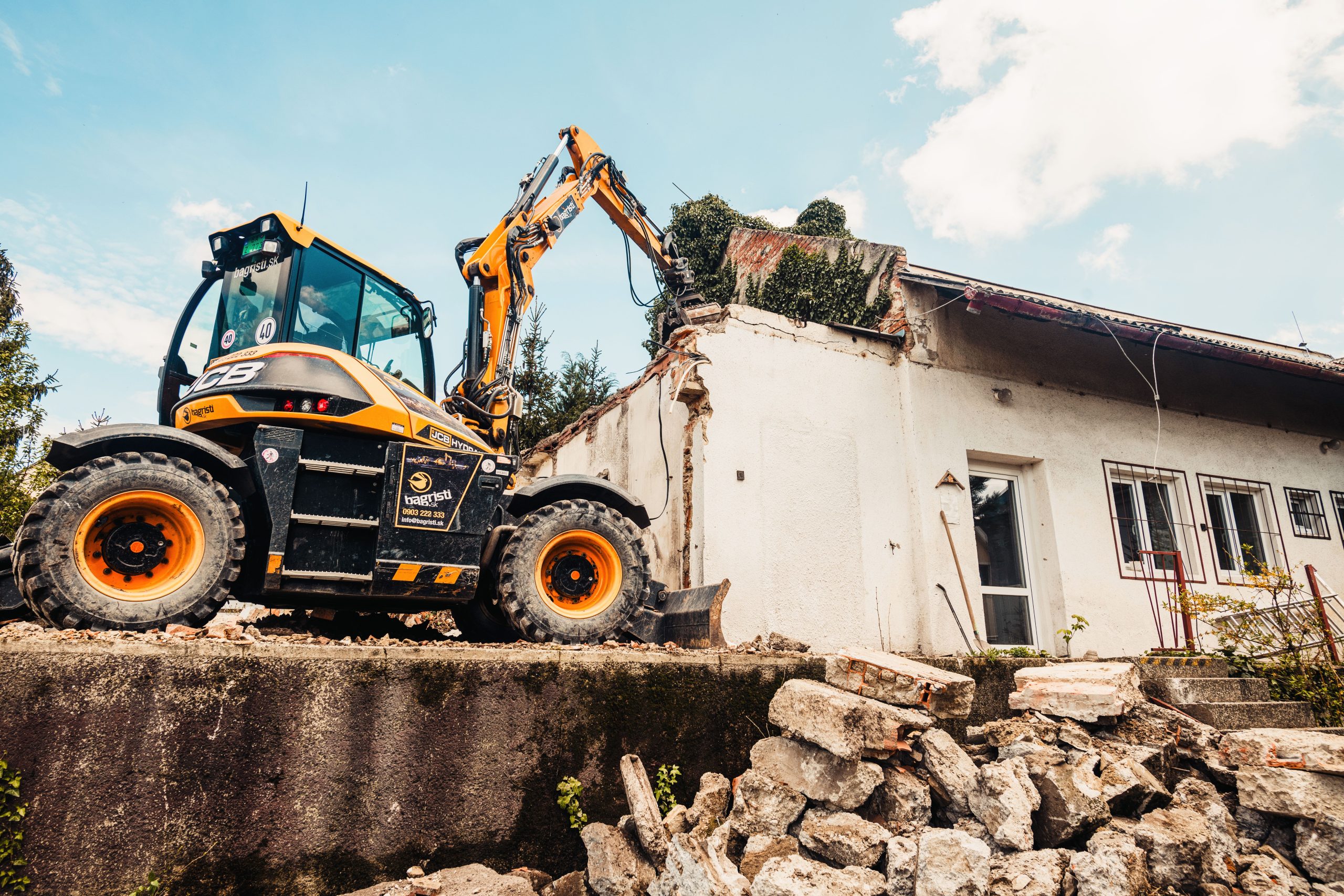 Powerful excavator tearing down an old house during a demolition project, illustrating when it's time to knock down rather than renovate