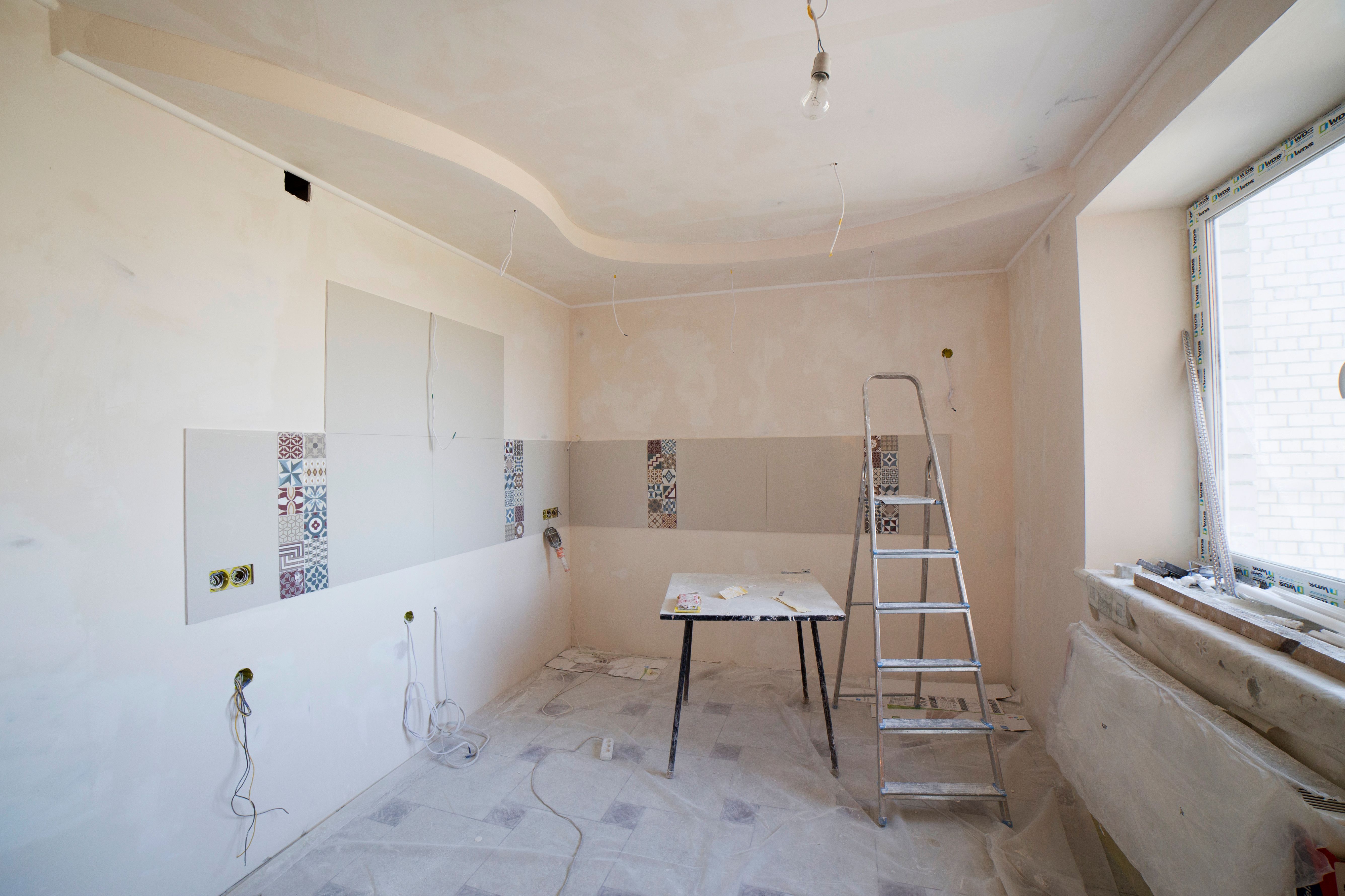 Spacious kitchen under renovation with ladder and tools showcasing a remodel in progress