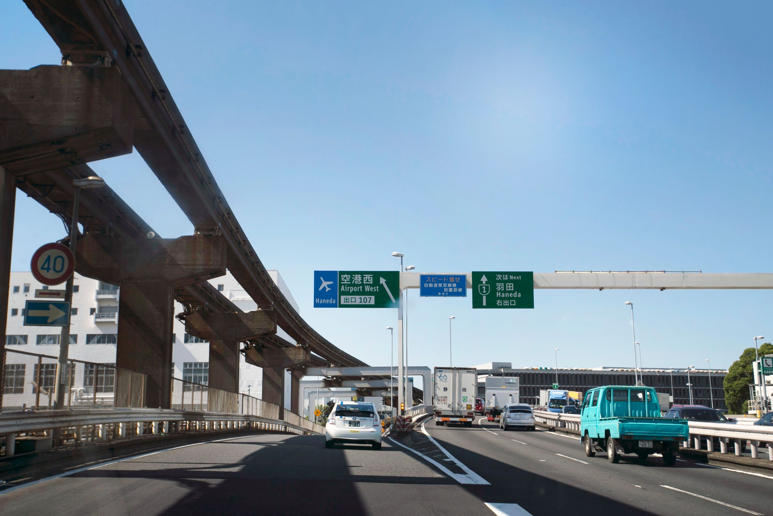Cars traveling on an airport-bound highway beneath overhead directional signs.