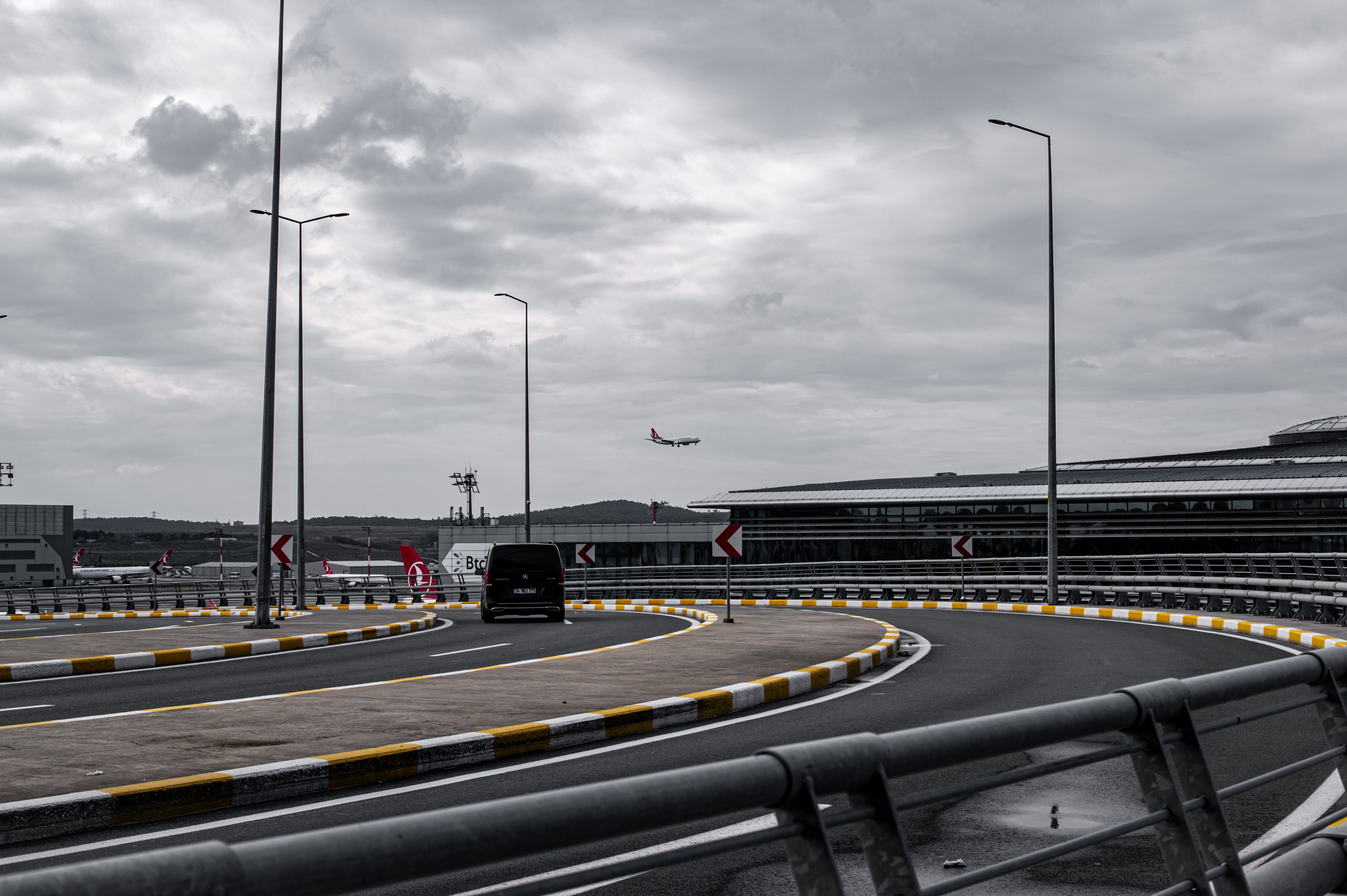 Airplane approaching an airport terminal above a curving access road.