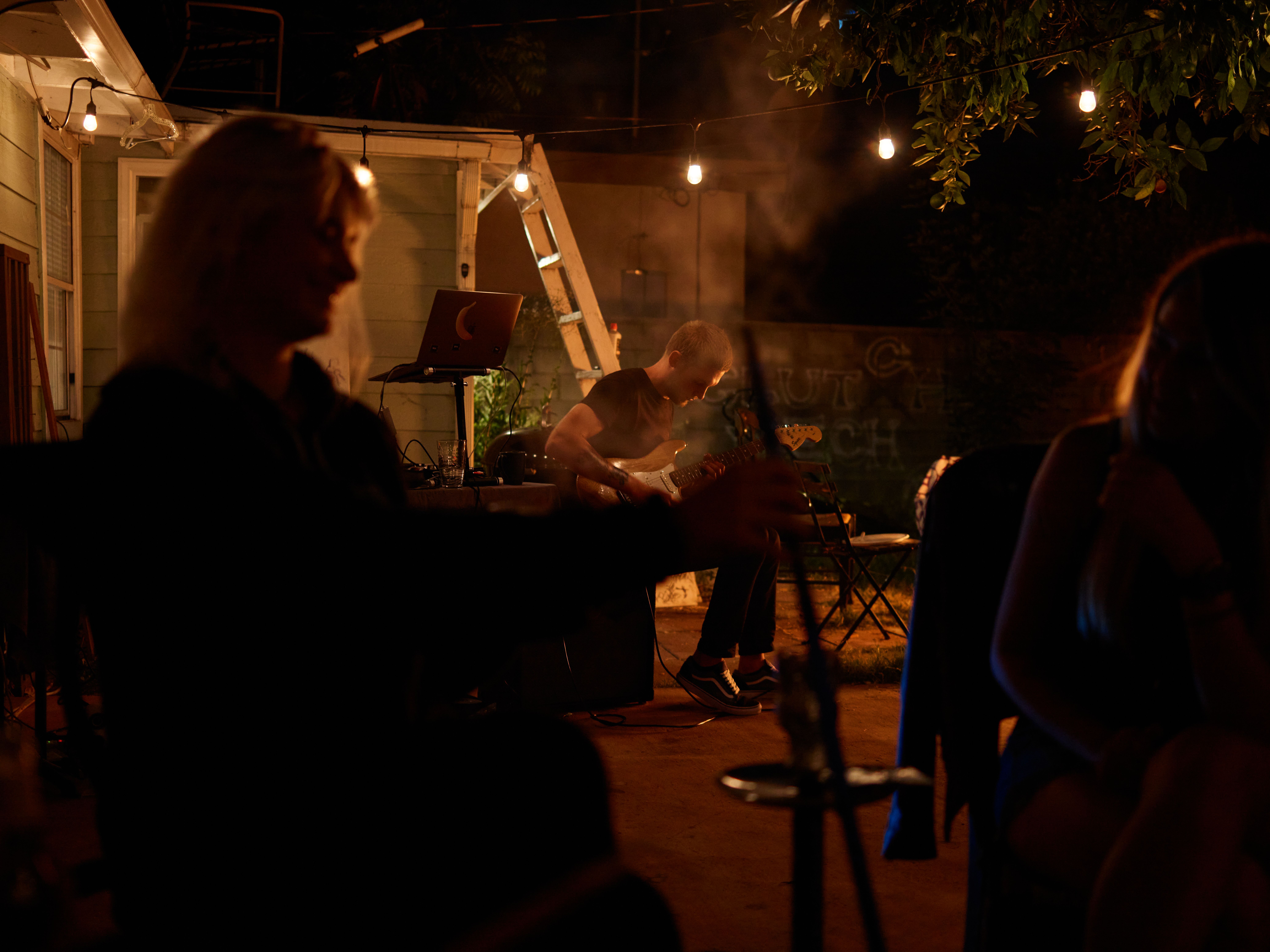 Backyard jam session with a guitarist, warm lighting, and a relaxed evening atmosphere.