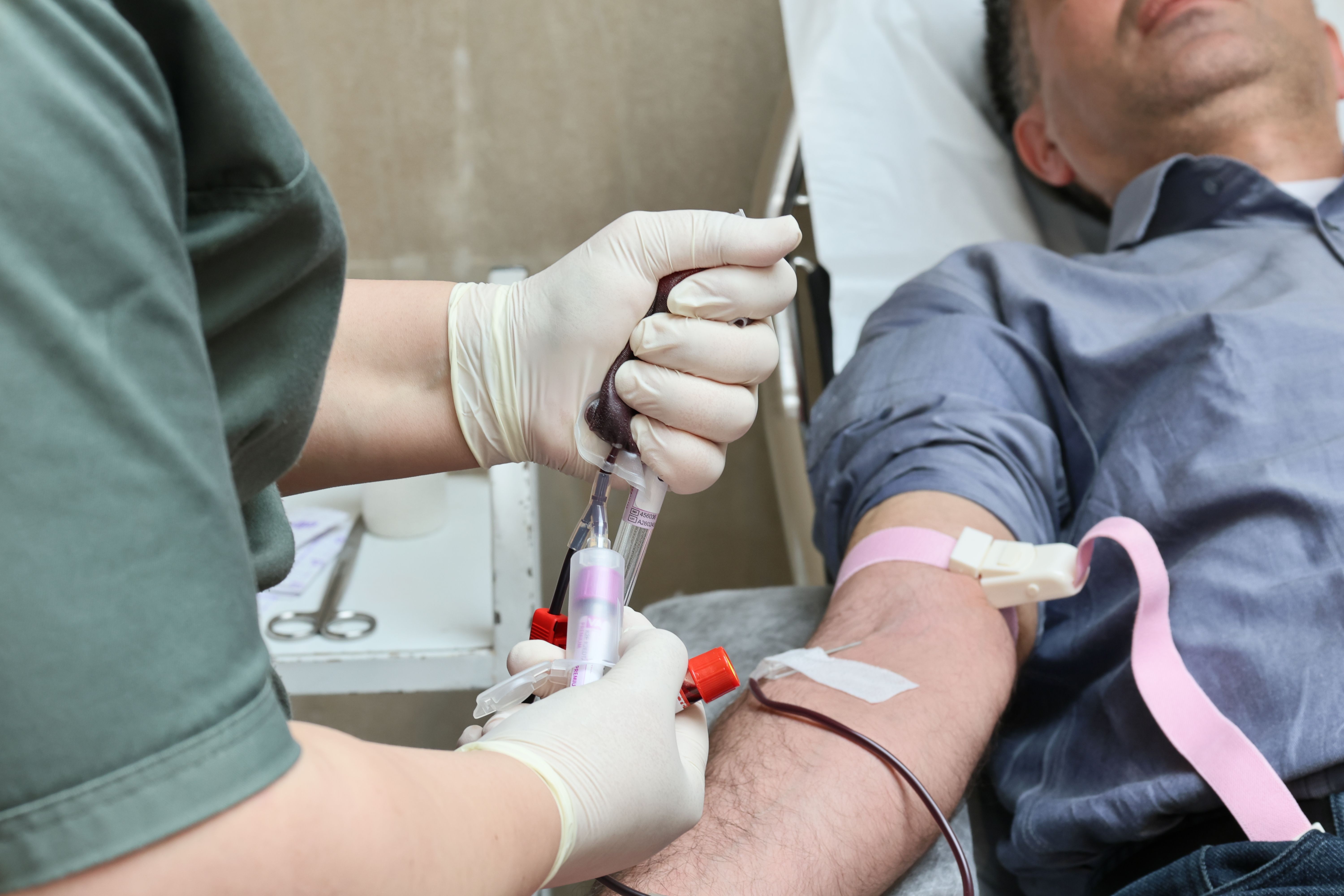 Healthcare professional collecting blood from a donor’s arm in a medical clinic.