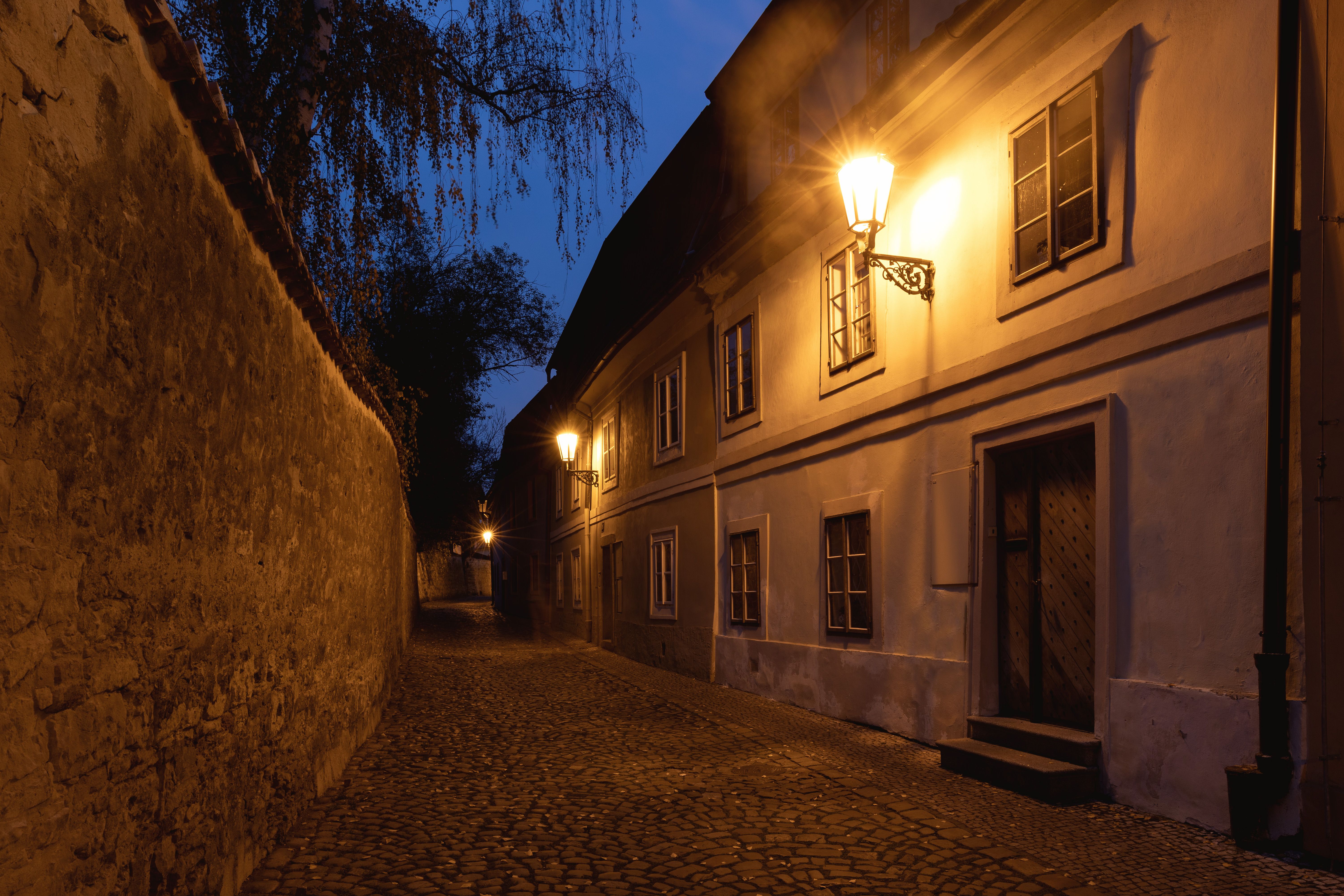 Illuminated cobblestone street in Prague lined with historic buildings at night