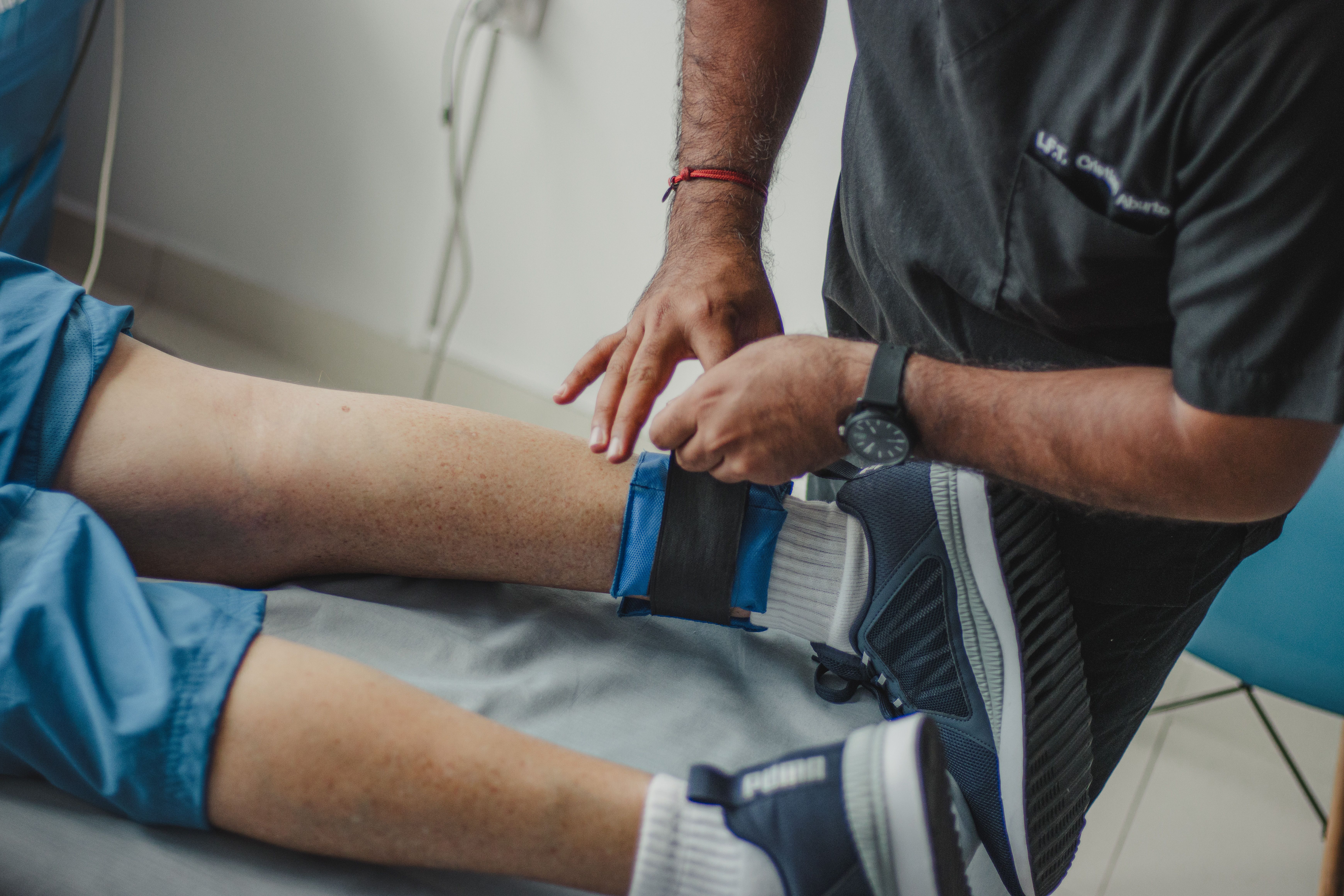 Physiotherapist adjusts a leg support during rehabilitation for an injury.