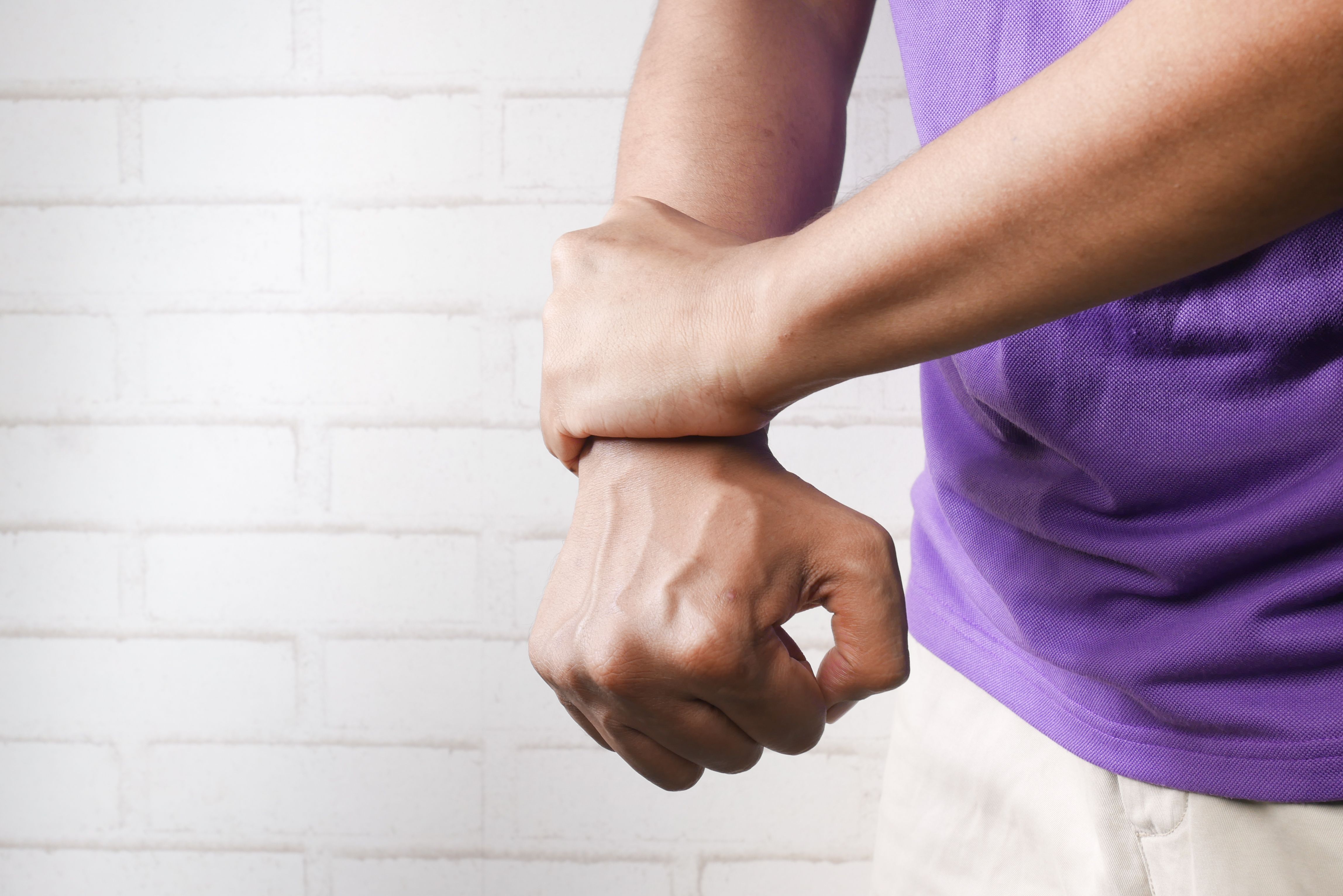 Close-up of a worker holding a painful wrist, illustrating a workplace injury that may worsen over time.